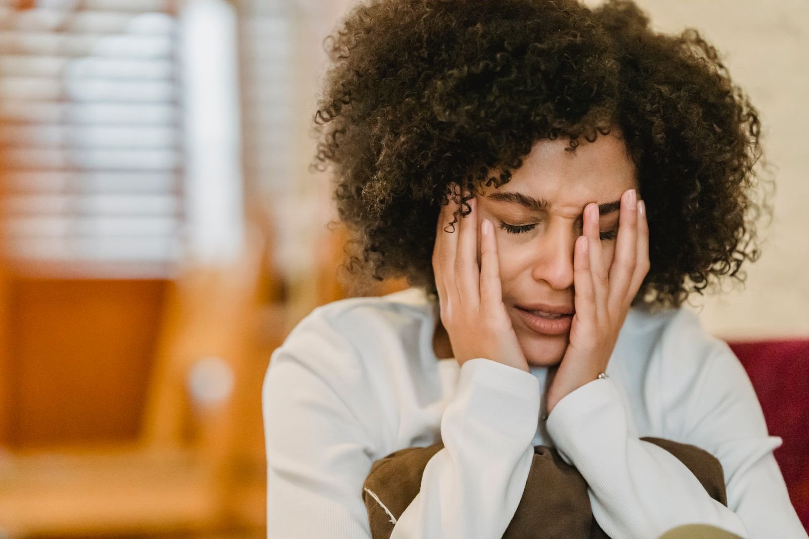 A woman pressing her hands to her face, overwhelmed by worry