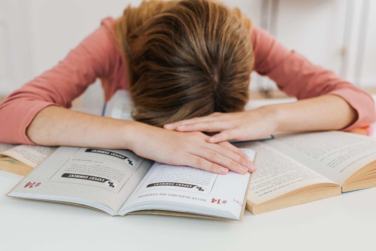 An overwhelmed student resting their head on an open book