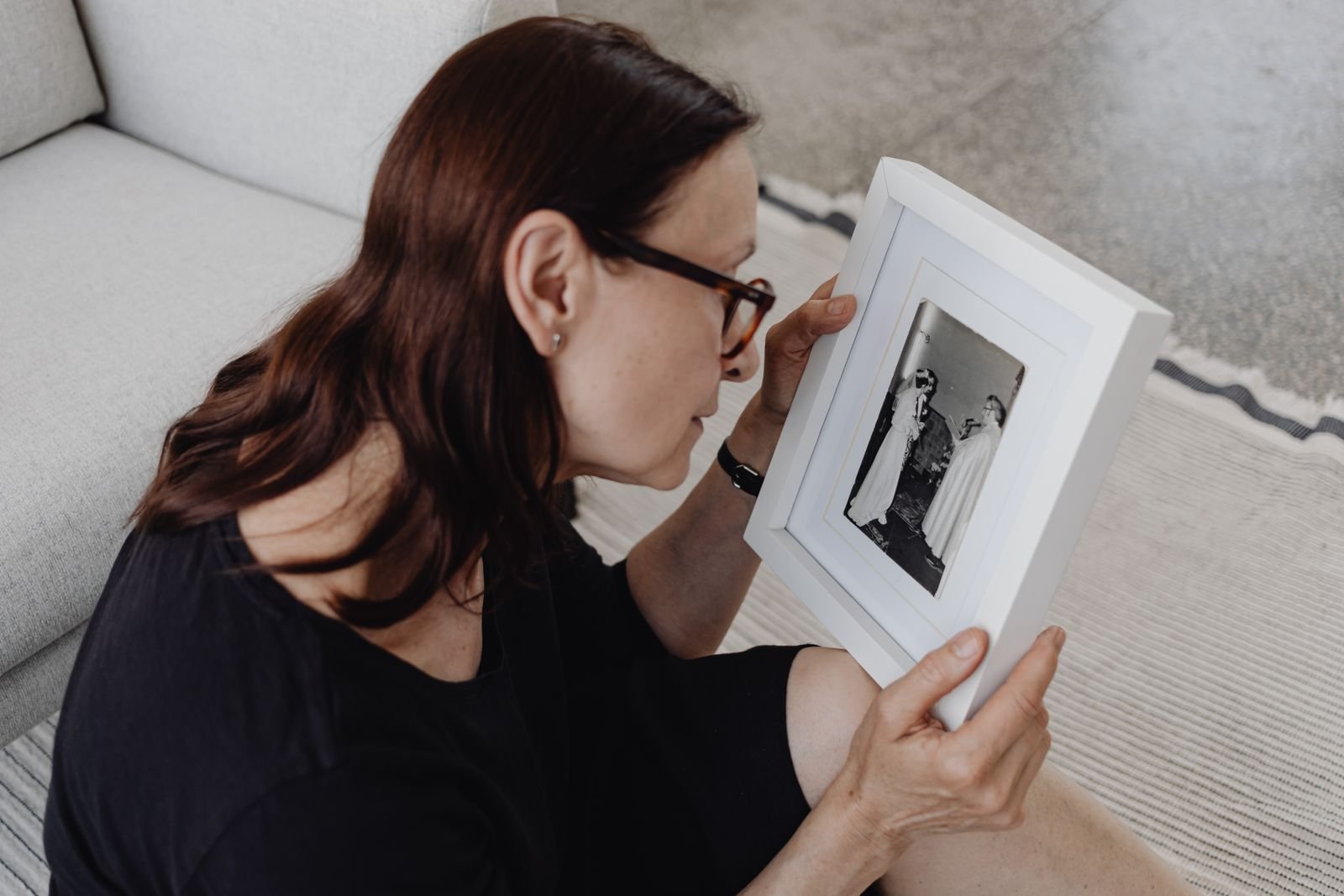 A woman holding a framed photograph in quiet reflection
