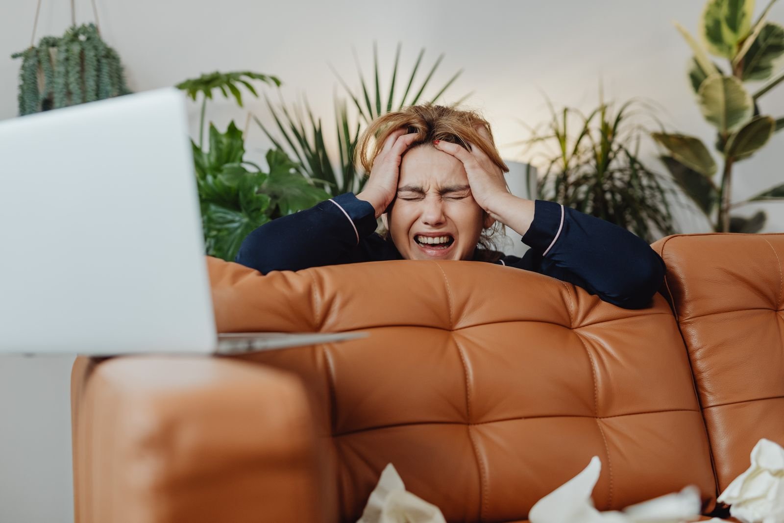 A frustrated woman sitting on a sofa with her eyes closed